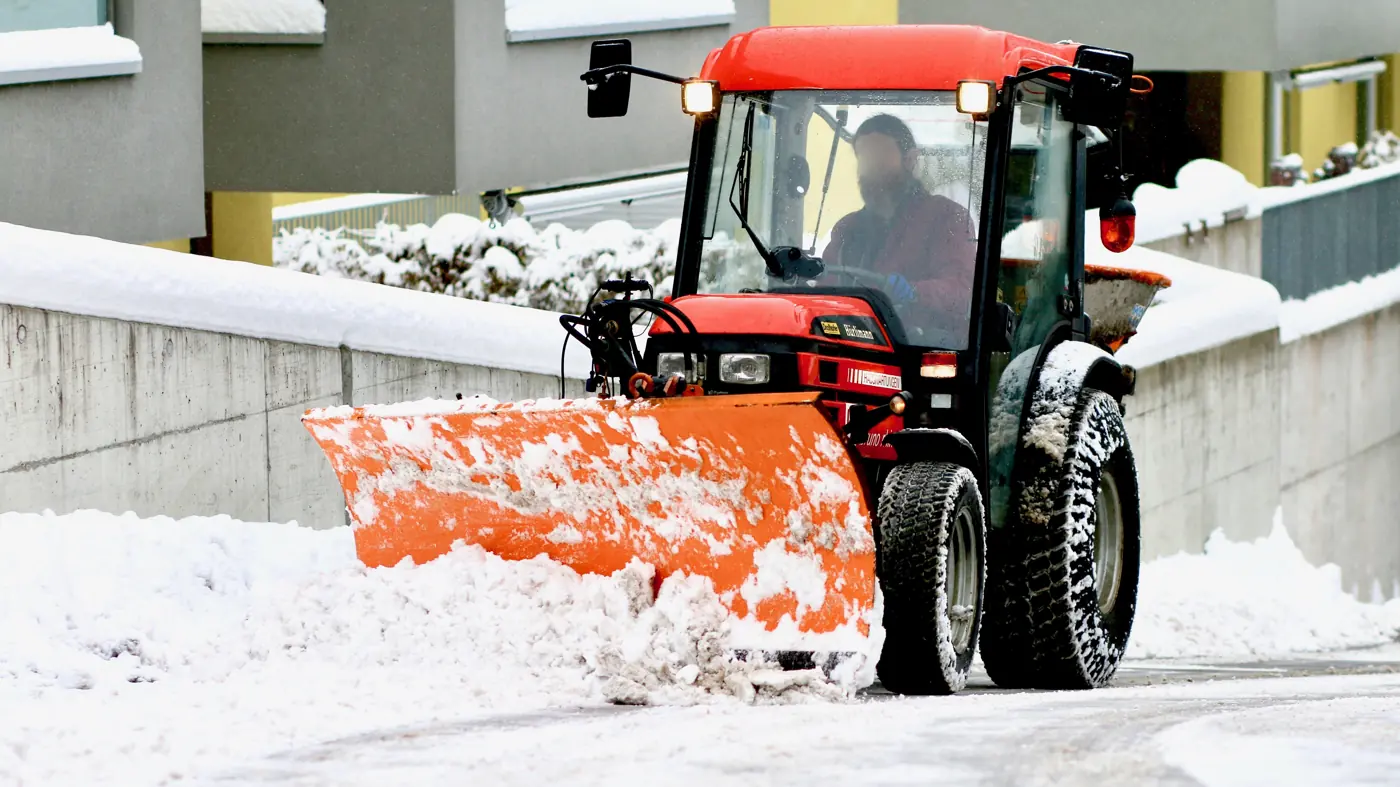 Ciągnik z pługiem odśnieża drogę